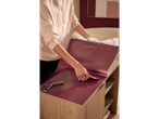 A person applying LIVARNO home decorative film with a geometric pattern to a wooden cabinet.
