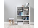 White cube storage unit with books and decorative items next to a gray stool.