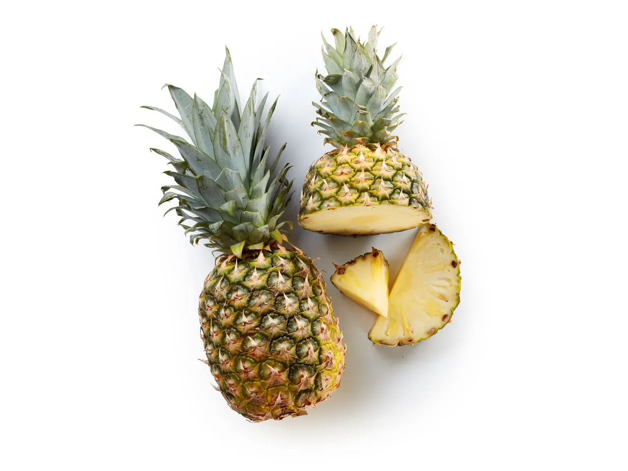 Ananas intero e tagliato su sfondo bianco.