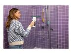Woman cleaning a purple tiled shower with a window vacuum cleaner.