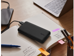 TRONIC 10000 mAh Power Bank charging a phone on a desk with a notebook and laptop.