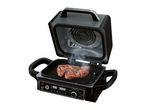 Open indoor grill with two steaks cooking, displaying digital controls and cooking modes.
