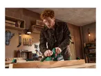 Man planing wood with an electric planer in a workshop.
