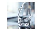 Clear water being poured into a transparent glass, creating splashes and ripples.