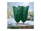 Two small garden trees covered in green winter protection bags in a snowy garden.