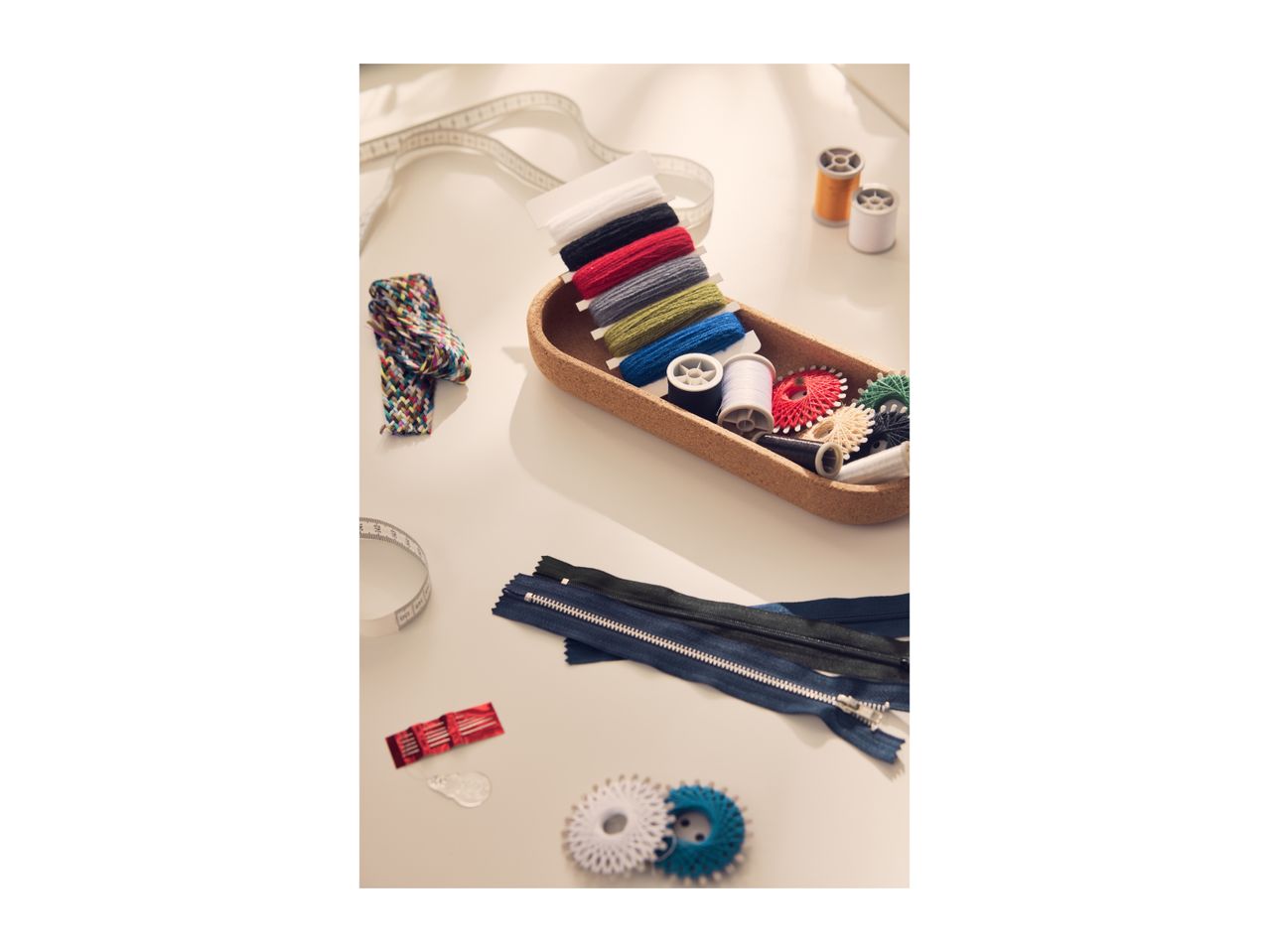 A collection of sewing accessories including threads, zippers, and measuring tapes on a table.