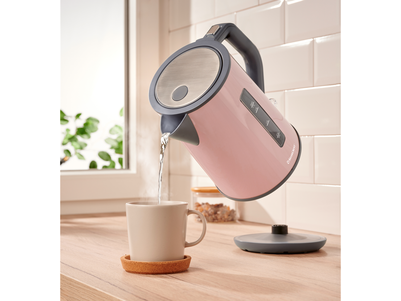 A pink Silvercrest kettle pours hot water into a mug.