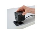 Hand placing a black cube-shaped power strip with multiple outlets and USB ports onto a mounting base.