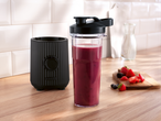 SILVERCREST® To Go Smoothie Maker with a berry smoothie, fresh fruit, and milk on a wooden counter.