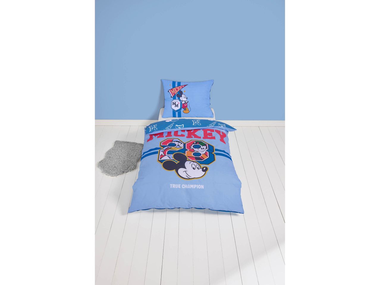 Mickey Mouse themed duvet cover set with a pillow on a white wooden floor.