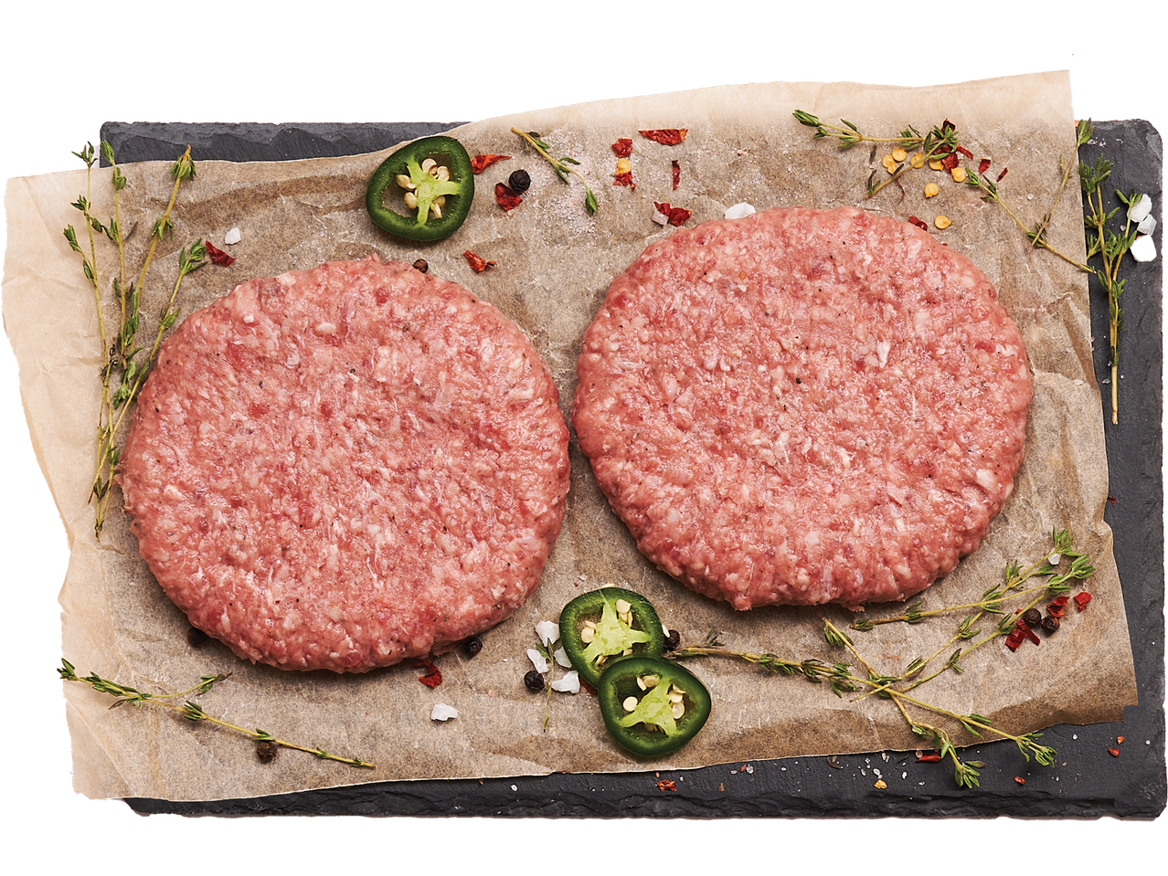Две сурови телешки кюфтета върху хартия за печене с билки, подправки и резени халапеньо.