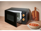 Black SILVERCREST microwave oven with open door, a bowl of tomato soup on the right.