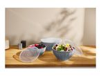 Three grey bowls with lids, two filled with berries and salad, on a wooden counter.