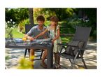 Father and daughter playing dominoes on a garden table with chairs in a sunny garden.