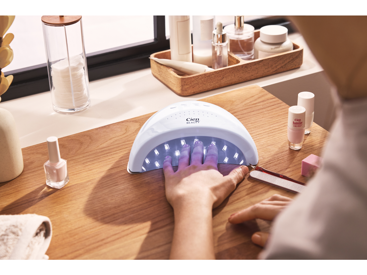 Lâmpada LED UV Cien Beauty para unhas, com uma mão por baixo, vernizes e acessórios de manicure.
