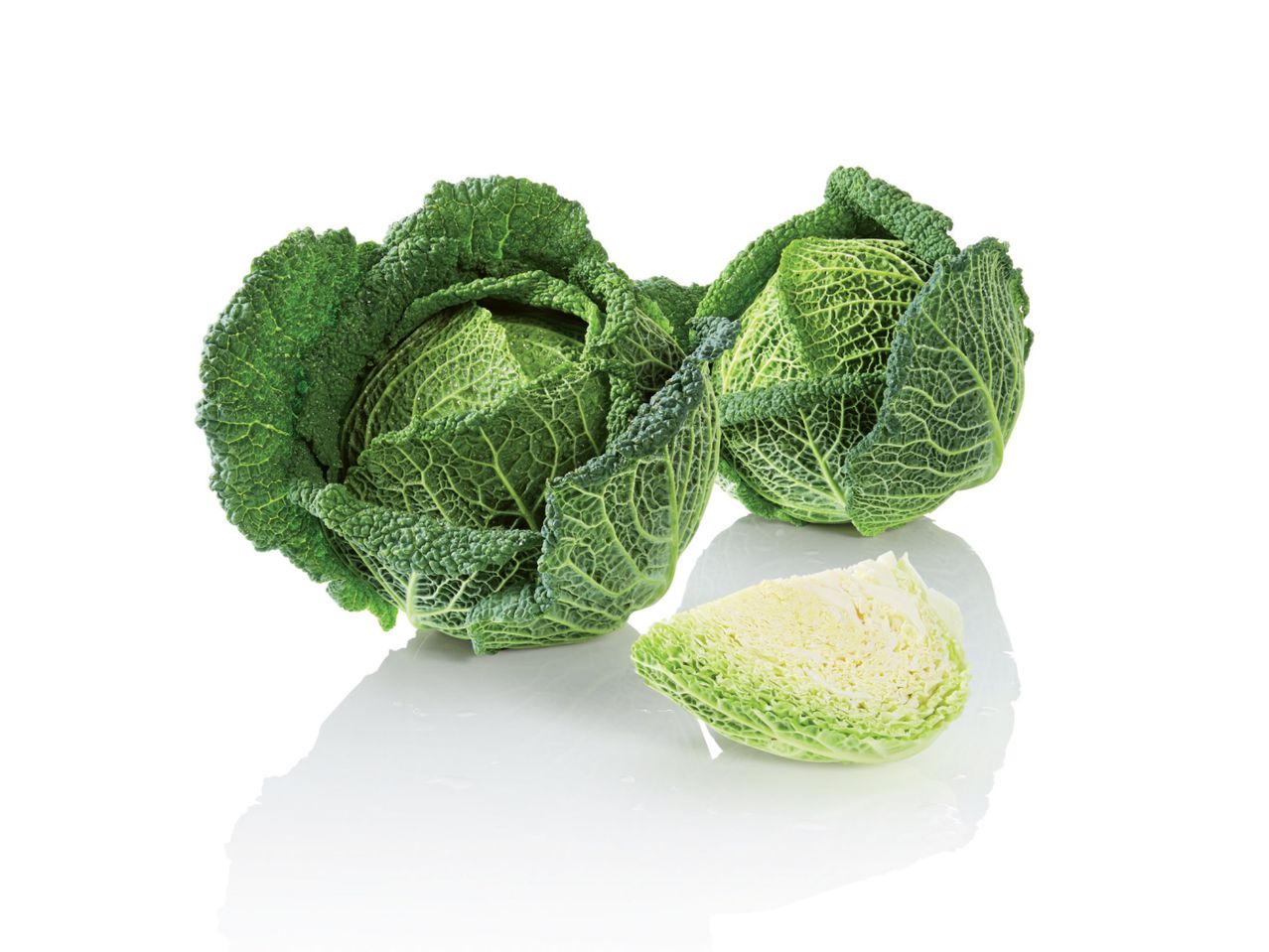 Dvije glavice kelja i jedna prerezana četvrtina kelja na bijeloj pozadini.