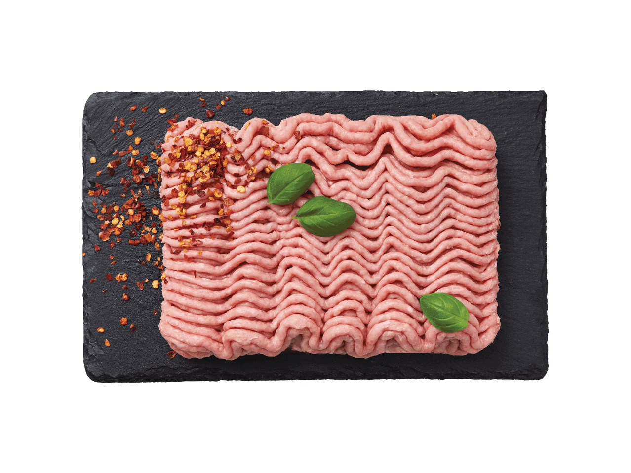 Šviežia malta mėsa su čili dribsniais ir baziliko lapeliais ant juodos lentelės.