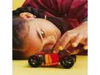 Girl playing with a red and yellow toy car on a yellow background.