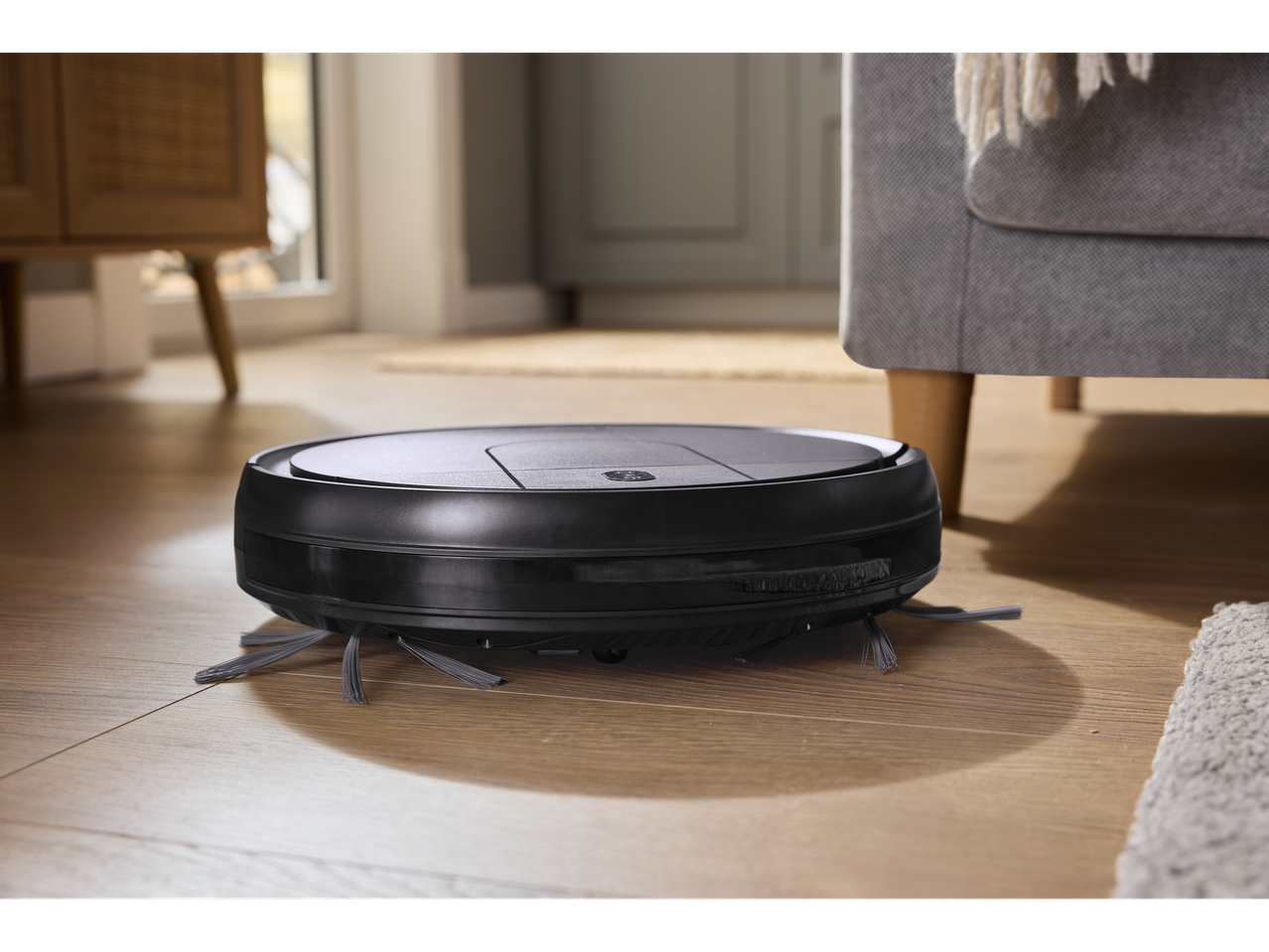 SILVERCREST® Robot Vacuum Cleaner on a wooden floor in a living room.