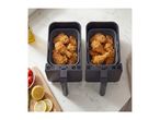 Two air fryer baskets filled with crispy fried chicken next to fresh lemon slices.