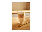 Latte macchiato in a tall glass with a golden spoon on a wooden surface.