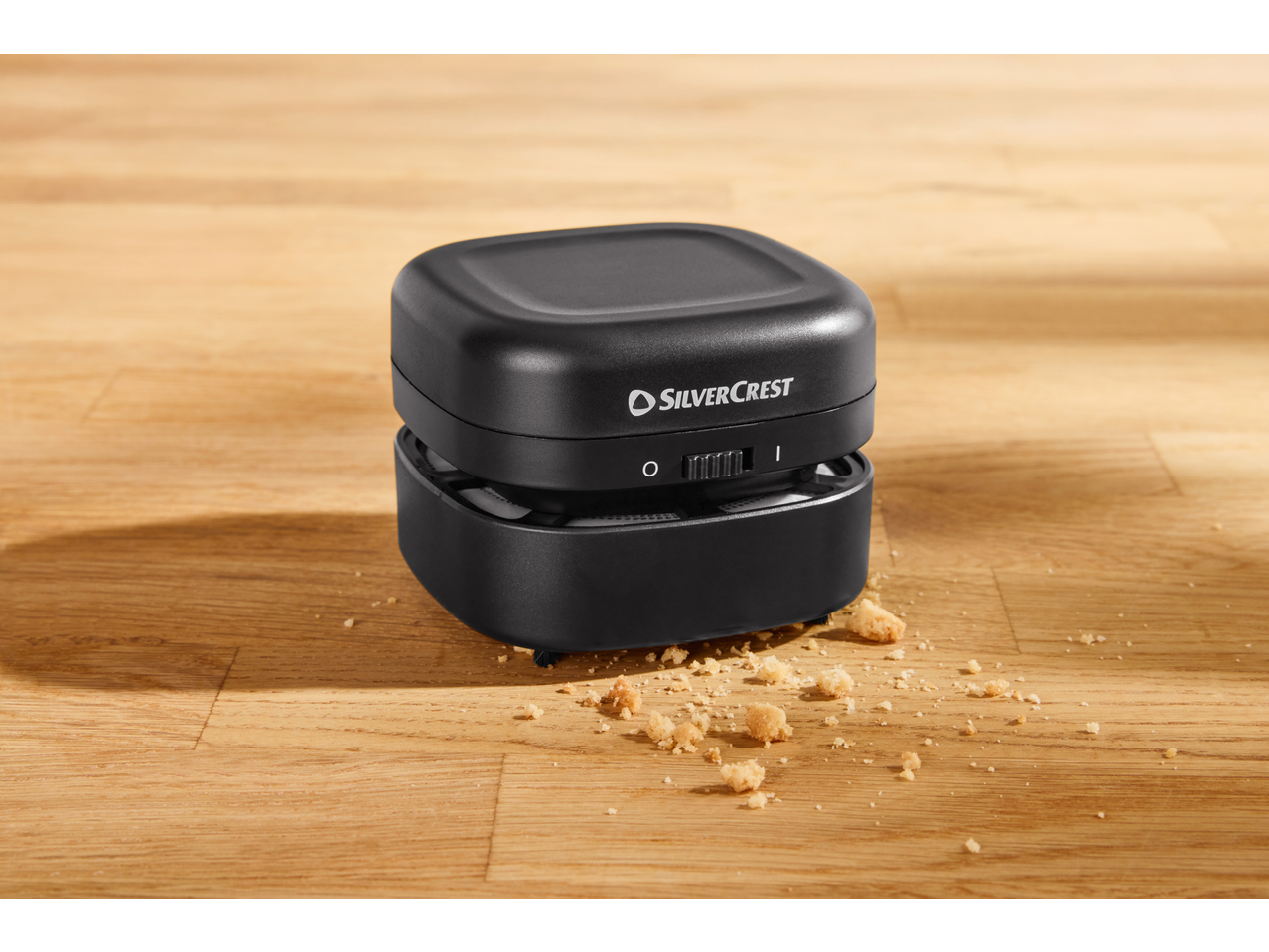 Mini aspirator de masă negru SILVERCREST curățând firimituri de biscuiți.