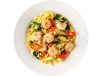 Shrimp pasta with red and green peppers and spinach on a white plate