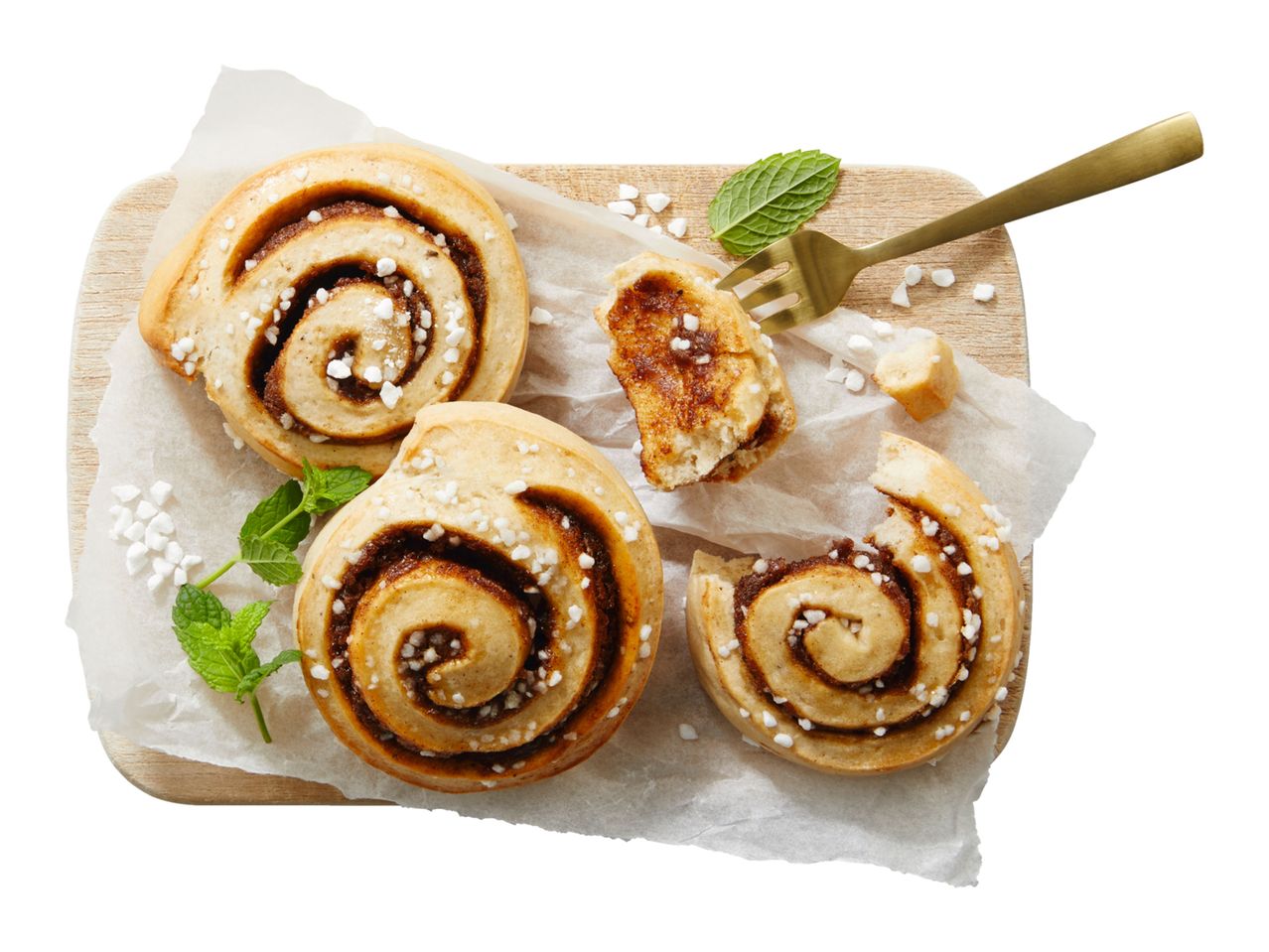 Cinnamon rolls with pearl sugar and mint on a wooden board with a fork.