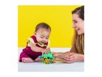 Baby and adult playing with a colorful frog-shaped rattle toy on a yellow background.