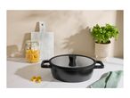 Black cooking pot with lid, pasta in a jar, basil plant, and cutting boards.
