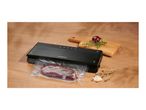 Black vacuum sealer packaging a piece of meat on a wooden table