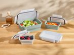 Collapsible food containers with salad, peppers, and berries on a wooden table.
