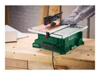 A person wearing gloves uses a green and white tile cutting machine on a wooden workbench.