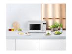A white Panasonic microwave oven on a kitchen counter with food and plants.