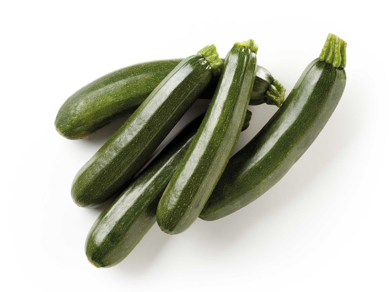 Zucchine verdi fresche disposte su sfondo bianco.