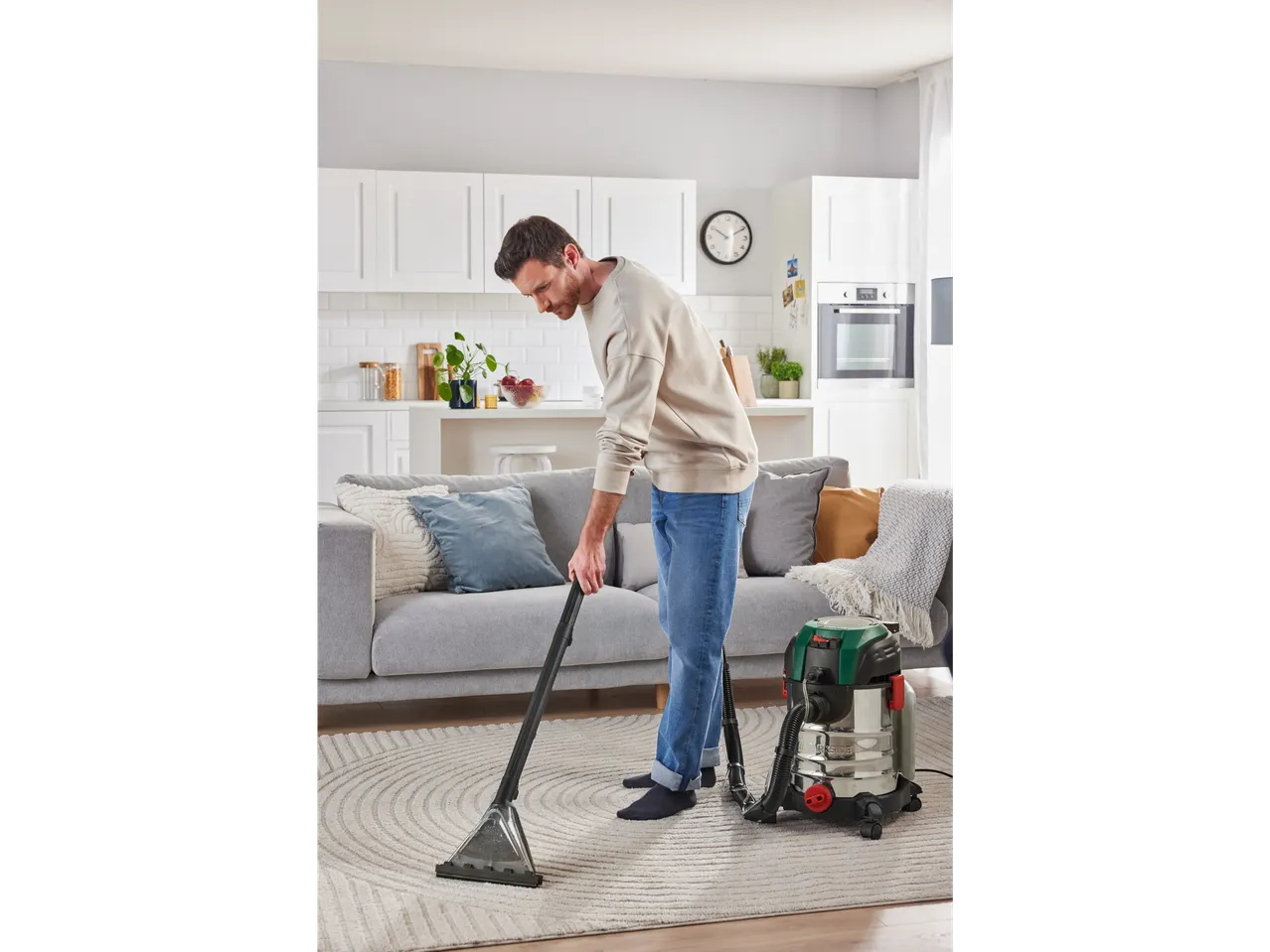A man cleans a rug with a Parkside wet and dry vacuum cleaner in a modern living room.
