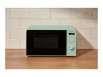 Mint green microwave on a wooden countertop with white tiled backsplash