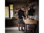 A man in Parkside workwear uses a file on a workbench in his workshop.