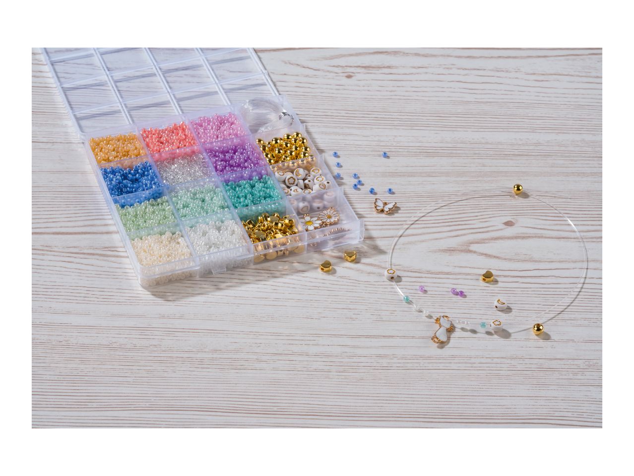 Bead organizer with colorful beads, charms, and a partially strung necklace on a wooden surface.