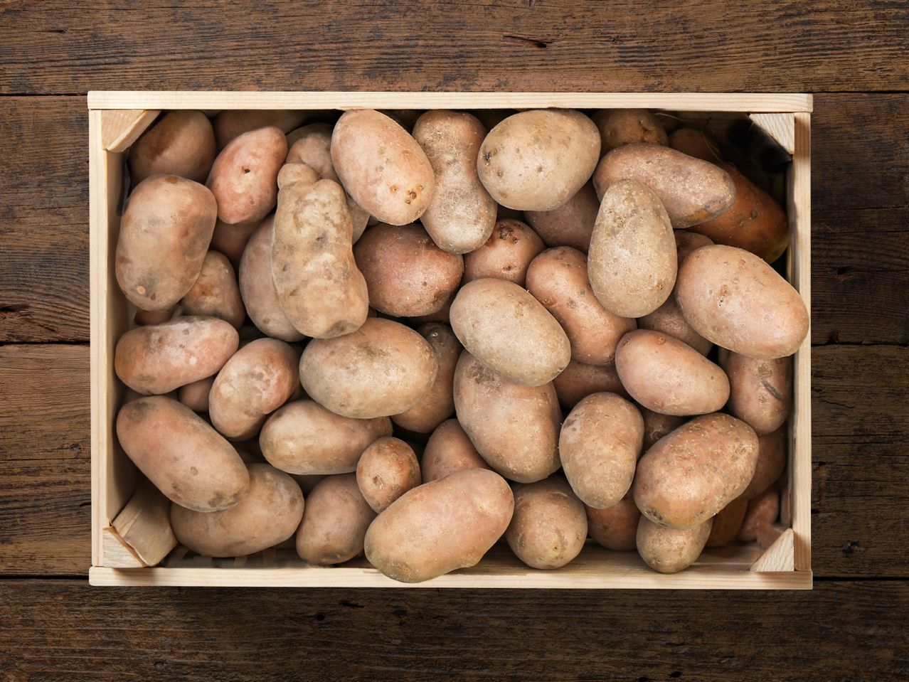 Una cassetta di legno piena di patate rustiche.