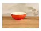 Red bowl on a wooden table with plant shadows on the wall