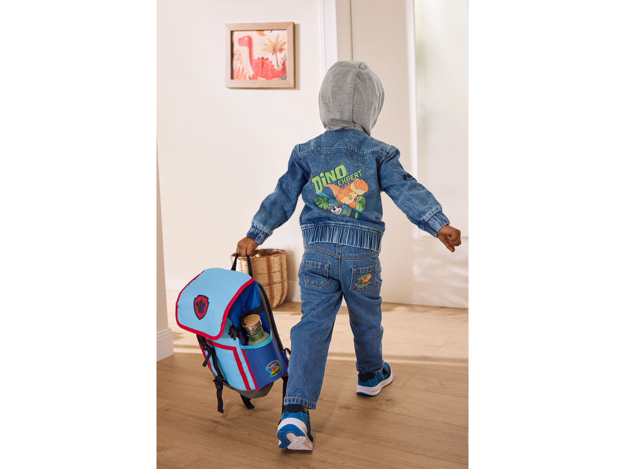 Criança com casaco de ganga LUPILU com dinossauro e mochila PAW Patrol.