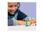 A smiling child playing with a toy hamster and a purple flower.