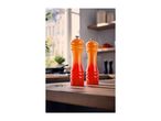 Two orange and red salt and pepper grinders on a wooden kitchen counter.