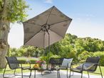 Outdoor patio set with a dark grey umbrella, two chairs, a bench, and a table with fruit and drinks.