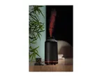 Black ribbed aroma diffuser emitting red-lit mist on a wooden table