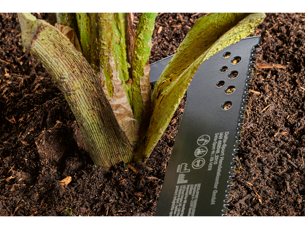 PARKSIDE® fierăstrău de grădină, cu lama sa zimțată, tăind o tulpină de plantă.