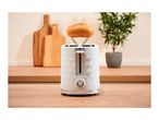White toaster with a bun warmer attachment on a wooden countertop