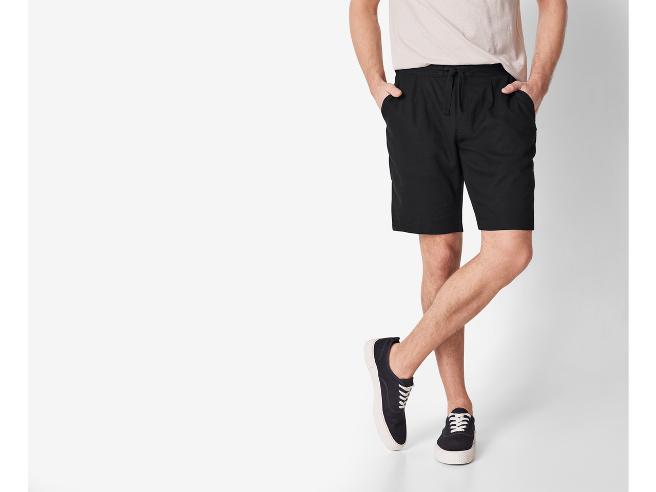 Bărbat purtând pantaloni scurți negri și adidași din pânză.