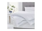 White duvet and pillows on a bed with a grey headboard, next to a plant on a table.
